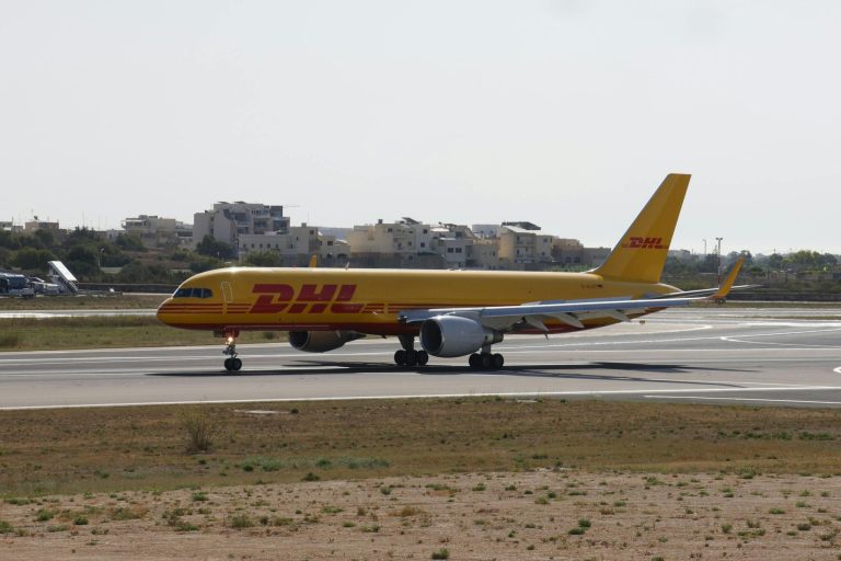 A DHL cargo plane positioned on an airport runway under clear skies.